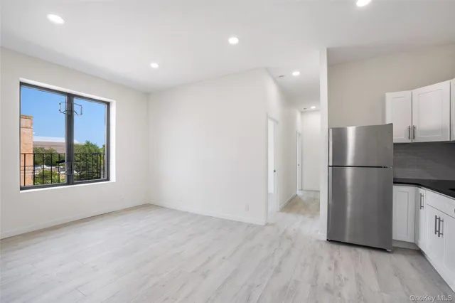 a view of kitchen with stainless steel appliances wooden floor and window