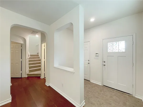 an empty room with wooden floor closet and windows
