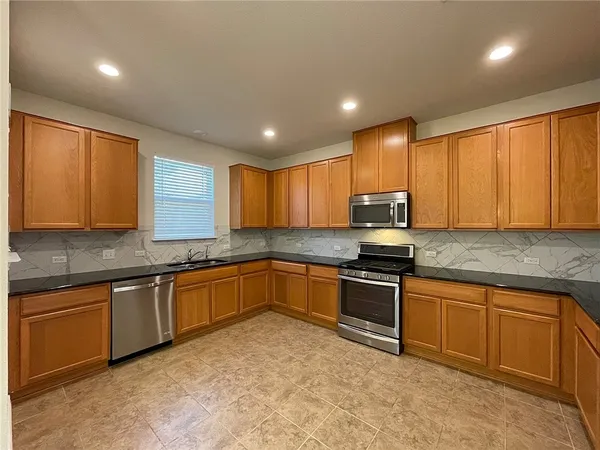 a kitchen with stainless steel appliances granite countertop a stove a sink and a microwave