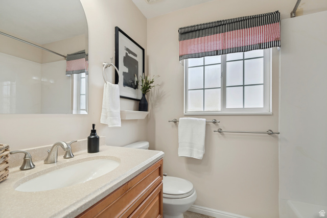 11798 Spiraea Way Draper, UT 84020 - Photo 14 of 21 Bathroom featuring a light-toned vanity with an integrated sink and brushed nickel faucet, an arched frameless mirror, and a window with privacy glass
