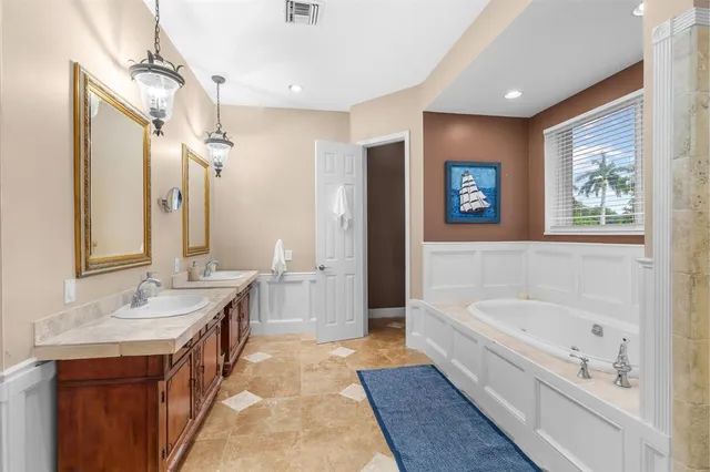 a spacious bathroom with a tub sink and mirror