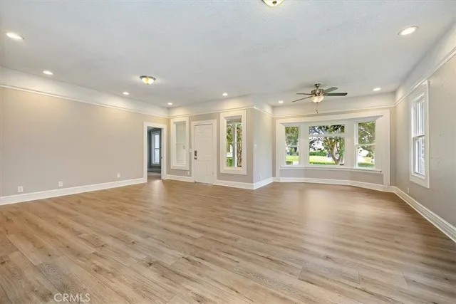 a view of an empty room with a window and wooden floor