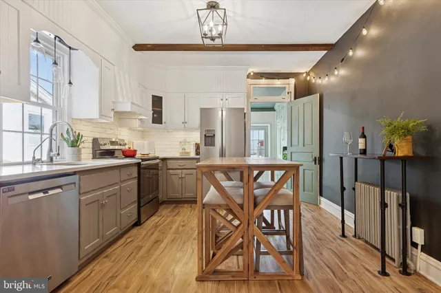a kitchen with stainless steel appliances a dining table chairs sink and cabinets