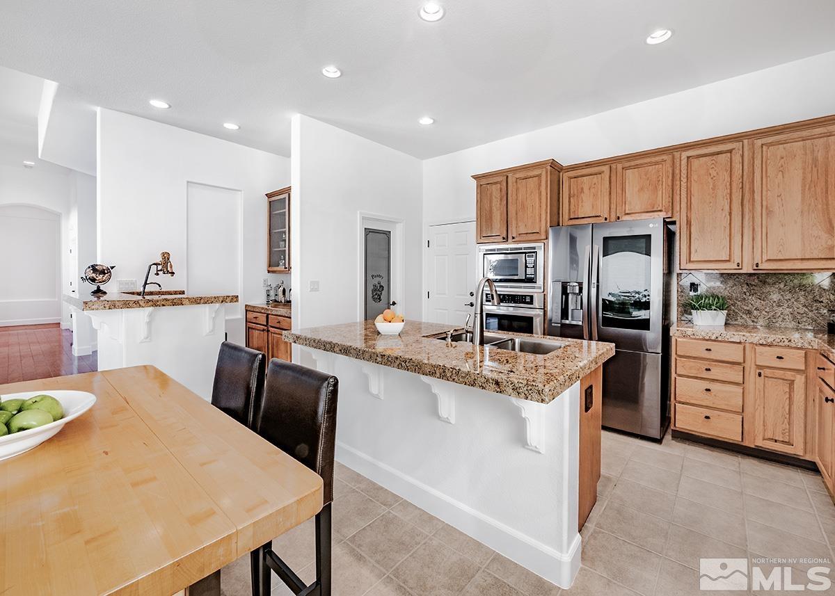 621 Rabbit Ridge Court Reno, NV 89511 - Photo 7 of 26 a large kitchen with kitchen island a stove a sink a refrigerator and a dining table with wooden floor