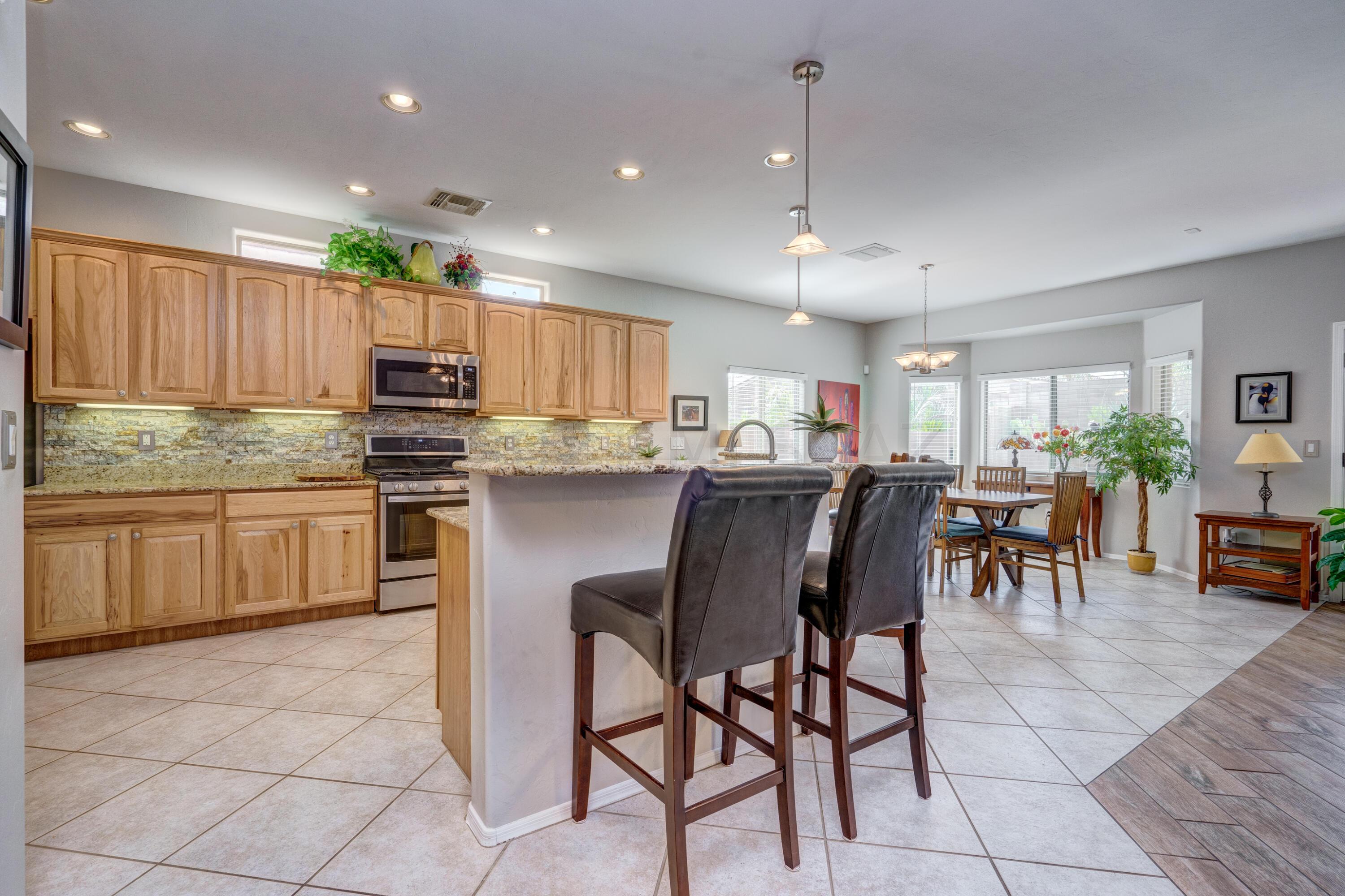 3639 East Northern Dancer Road Tucson, AZ 85739 - Photo 14 of 48 a kitchen with kitchen island granite countertop wooden cabinets a counter top space a sink stainless steel appliances and cabinets