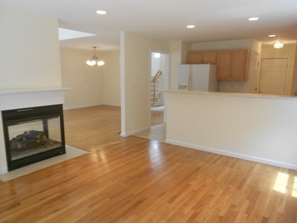 141 Lordvale Boulevard, Unit 141 Grafton, MA 01536 - Photo 12 of 23 a view of an empty room and kitchen with fireplace wooden floor