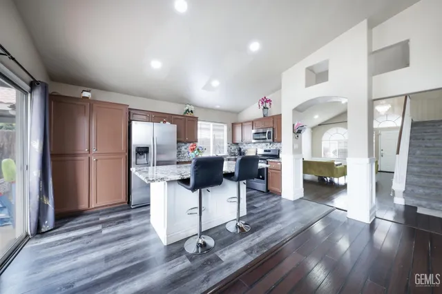 a kitchen with kitchen island granite countertop a sink refrigerator and microwave
