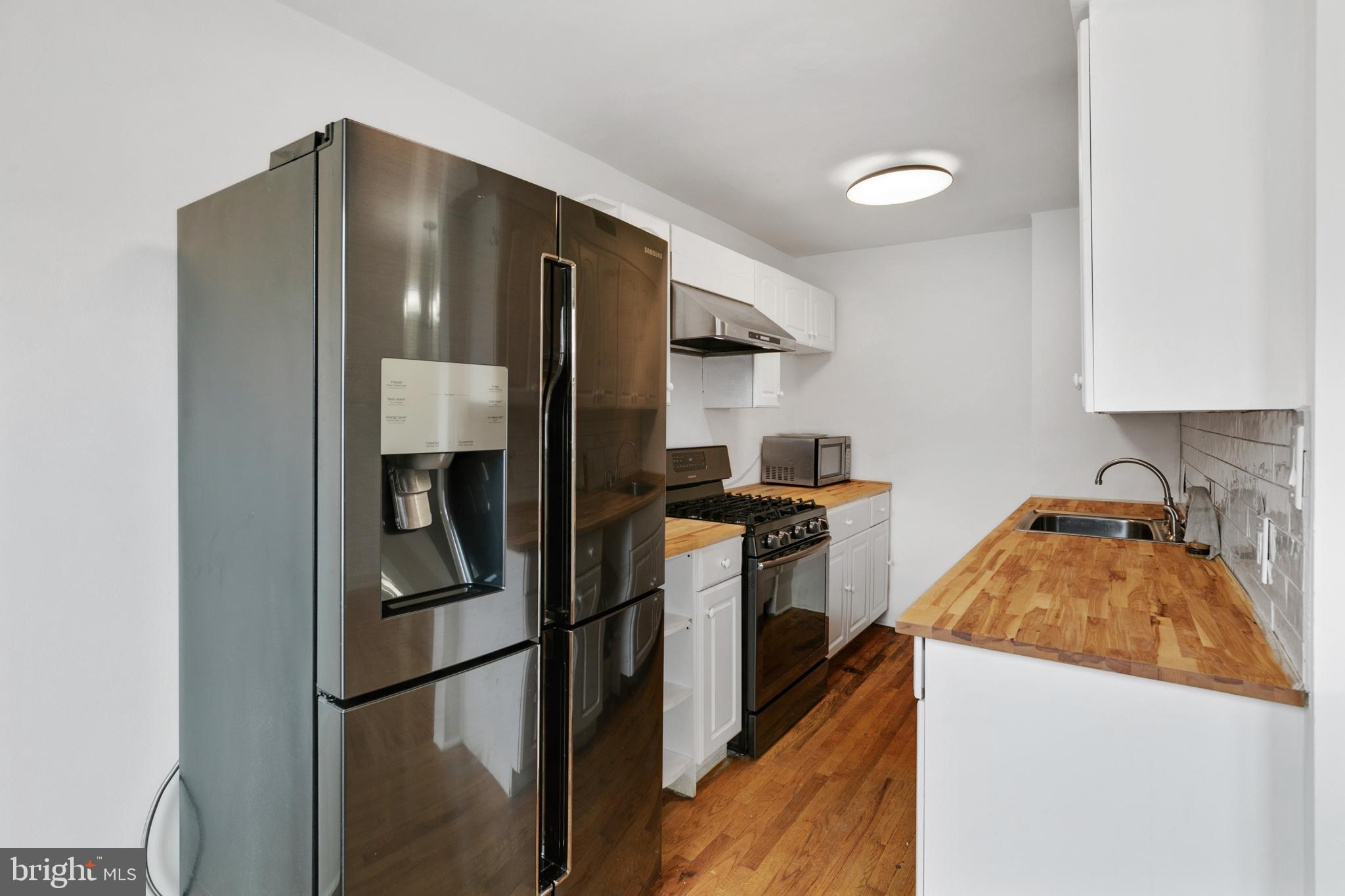 1828 South 29th Street Philadelphia, PA 19145 - Photo 9 of 32 a kitchen with stainless steel appliances granite countertop a refrigerator a stove and a sink