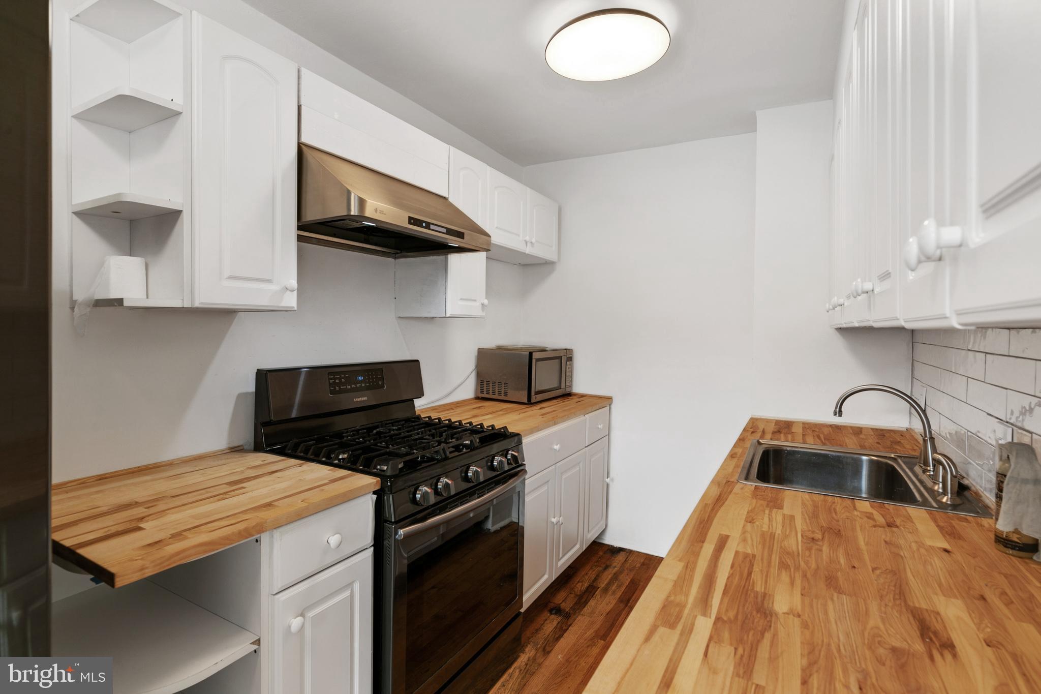 1828 South 29th Street Philadelphia, PA 19145 - Photo 10 of 32 a kitchen with stainless steel appliances granite countertop a stove a sink and a microwave