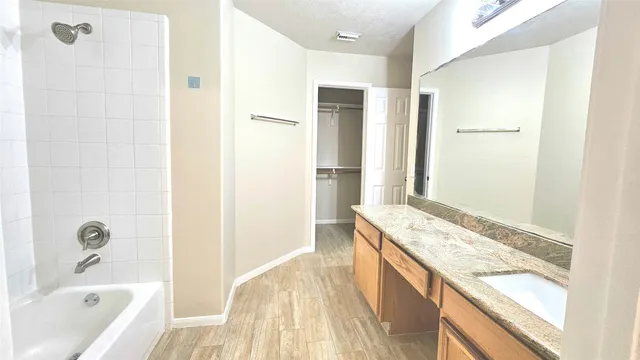 a bathroom with a granite countertop tub sink and mirror