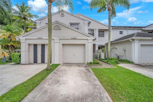 a view of a white house next to a yard with palm trees