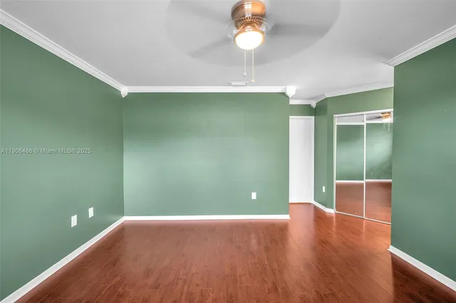 an empty room with wooden floor and fan