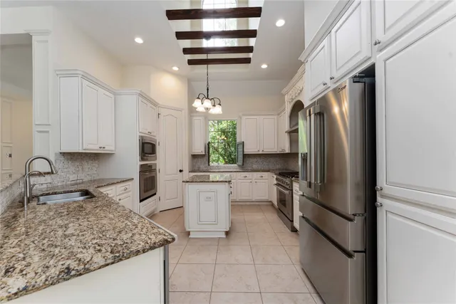 a kitchen with stainless steel appliances granite countertop a refrigerator a sink a stove and white cabinets