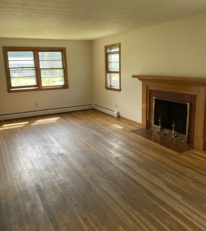 29 Justice Drive Amherst, MA 01002 - Photo 5 of 20 an empty room with wooden floor fireplace and windows