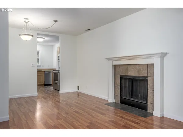 a view of an empty room with wooden floor and a fireplace