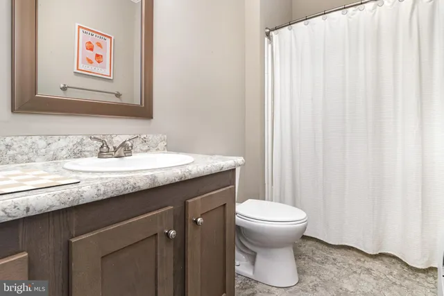 a bathroom with a granite countertop sink a toilet and a mirror