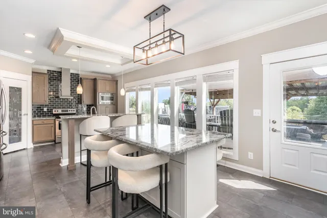 a dining room with furniture a chandelier and kitchen view