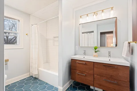 a bathroom with a double vanity sink mirror and bathtub