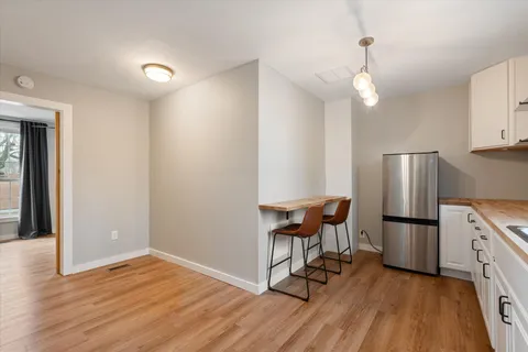 a view of kitchen with stainless steel appliances refrigerator stove and wooden floor