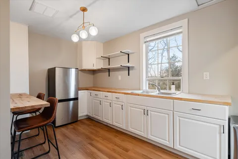 a kitchen with stainless steel appliances granite countertop a sink dishwasher a microwave oven a refrigerator with white cabinets and wooden floor