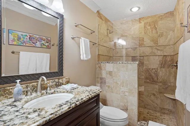 a bathroom with a granite countertop sink toilet a mirror and shower