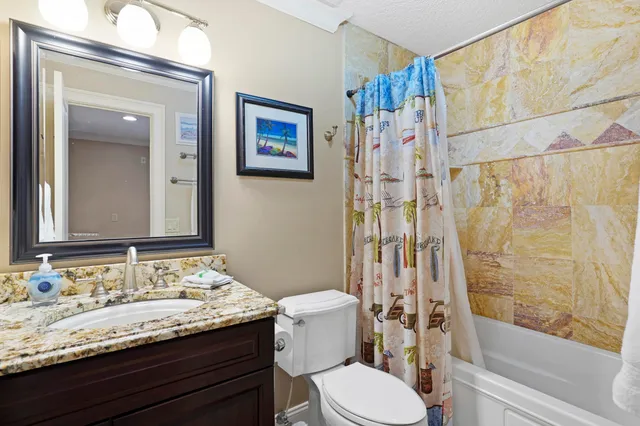 a bathroom with a granite countertop sink toilet and shower