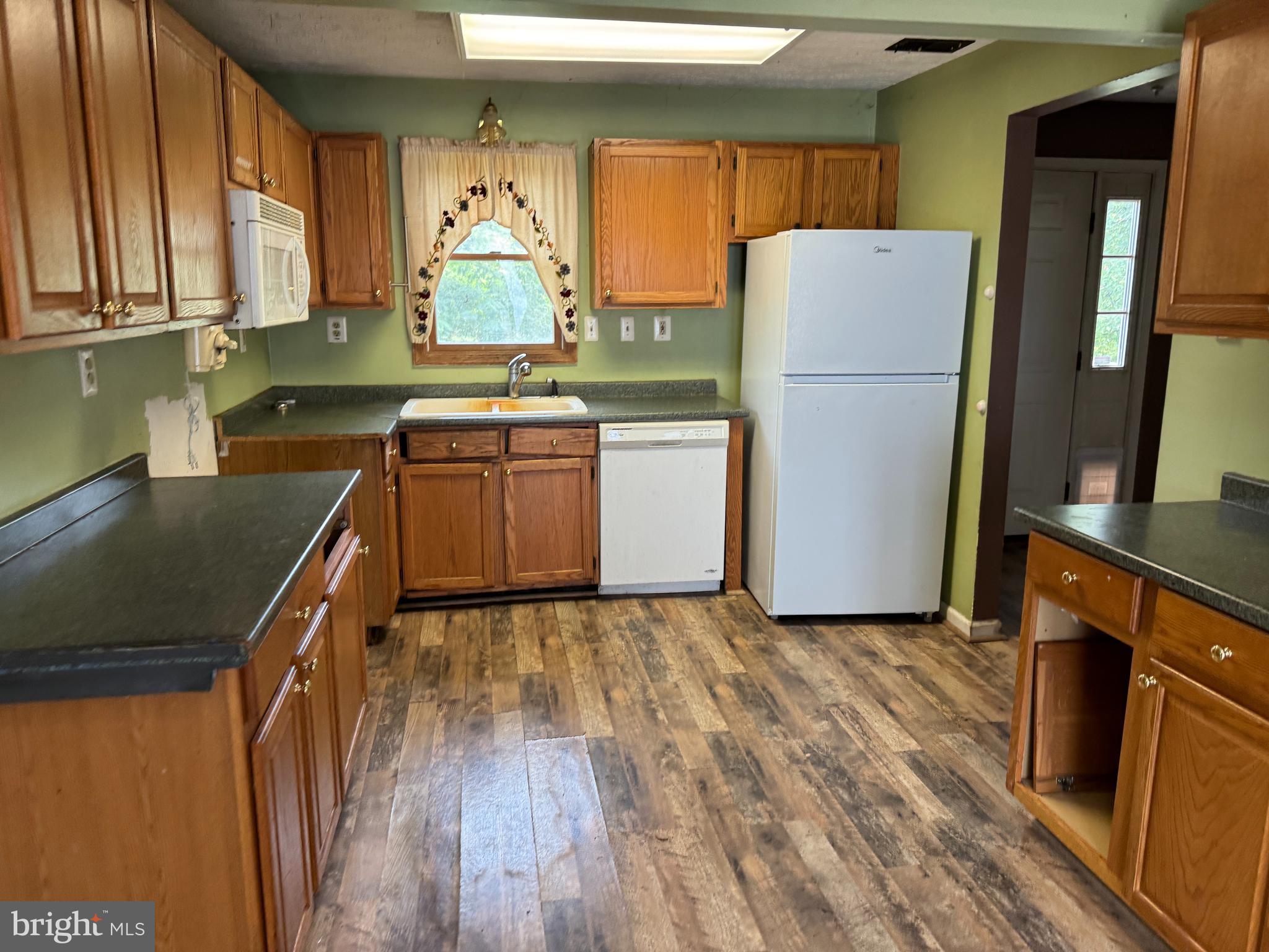 8922 Carpers Pike Yellow Spring, WV 26865 - Photo 7 of 23 a kitchen with a refrigerator a stove a sink dishwasher and wooden cabinets with wooden floor