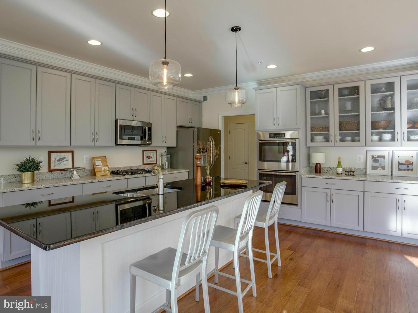 12504 Regwood Road Hydes, MD 21082 - Photo 3 of 28 a kitchen with stainless steel appliances kitchen island granite countertop a stove top oven a sink a refrigerator with a dining table and chairs