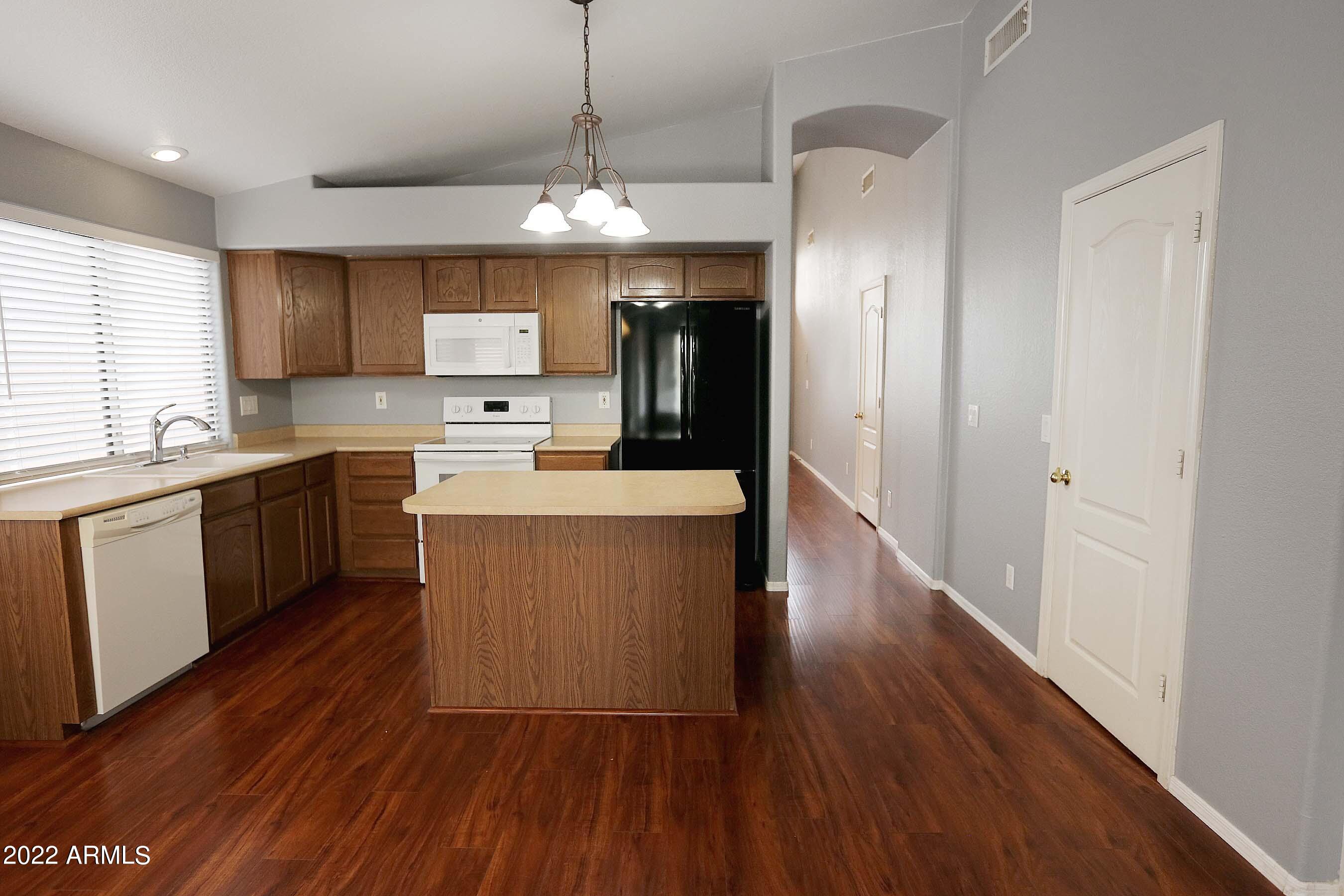 11217 West Edgemont Avenue Avondale, AZ 85392 - Photo 13 of 47 a kitchen with stainless steel appliances granite countertop a refrigerator a sink dishwasher a stove and white countertops with wooden floor