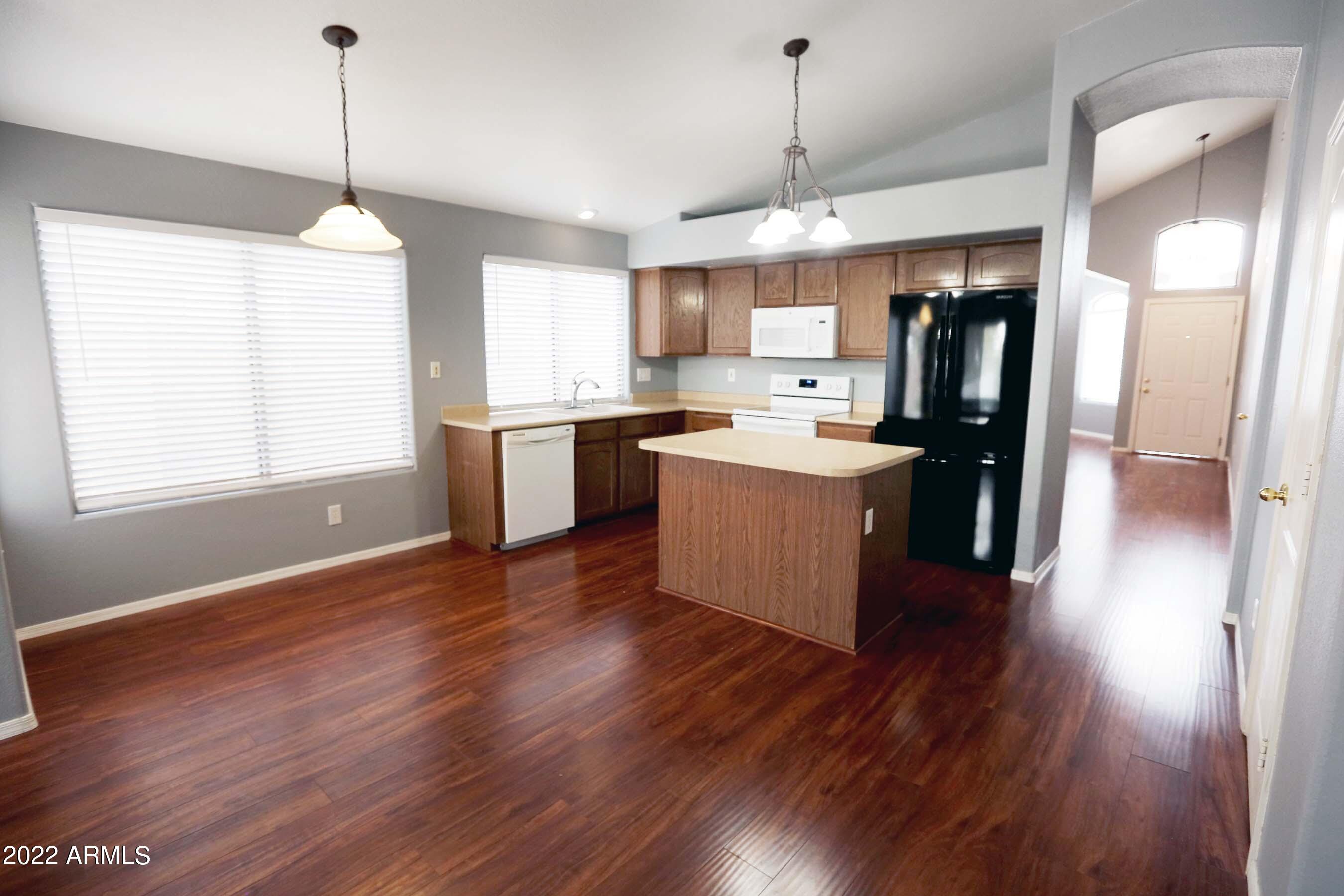 11217 West Edgemont Avenue Avondale, AZ 85392 - Photo 18 of 47 a kitchen with stainless steel appliances granite countertop a refrigerator a sink dishwasher a kitchen island with wooden floor and cabinets