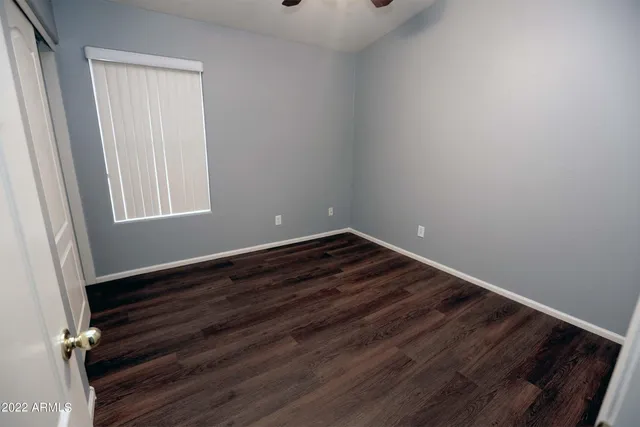 a view of empty room with window and wooden floor