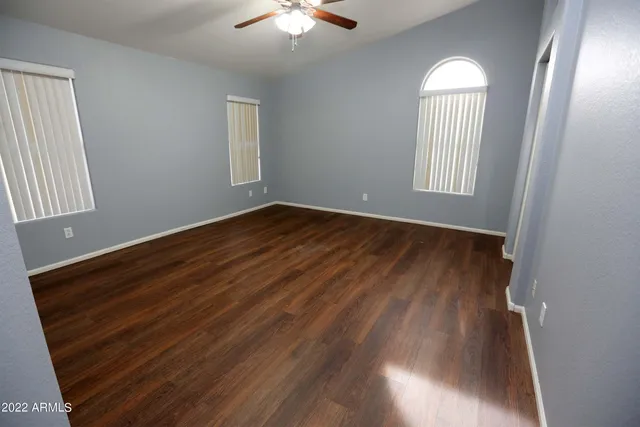 an empty room with wooden floor cabinet and windows