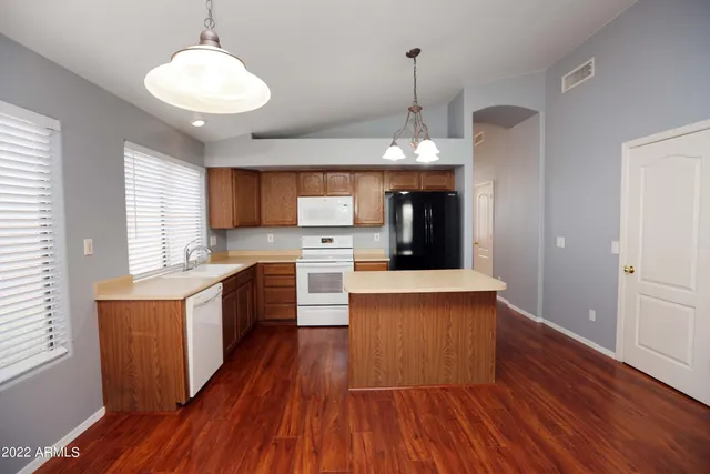 a large kitchen with stainless steel appliances granite countertop wooden floors a stove a sink and a refrigerator