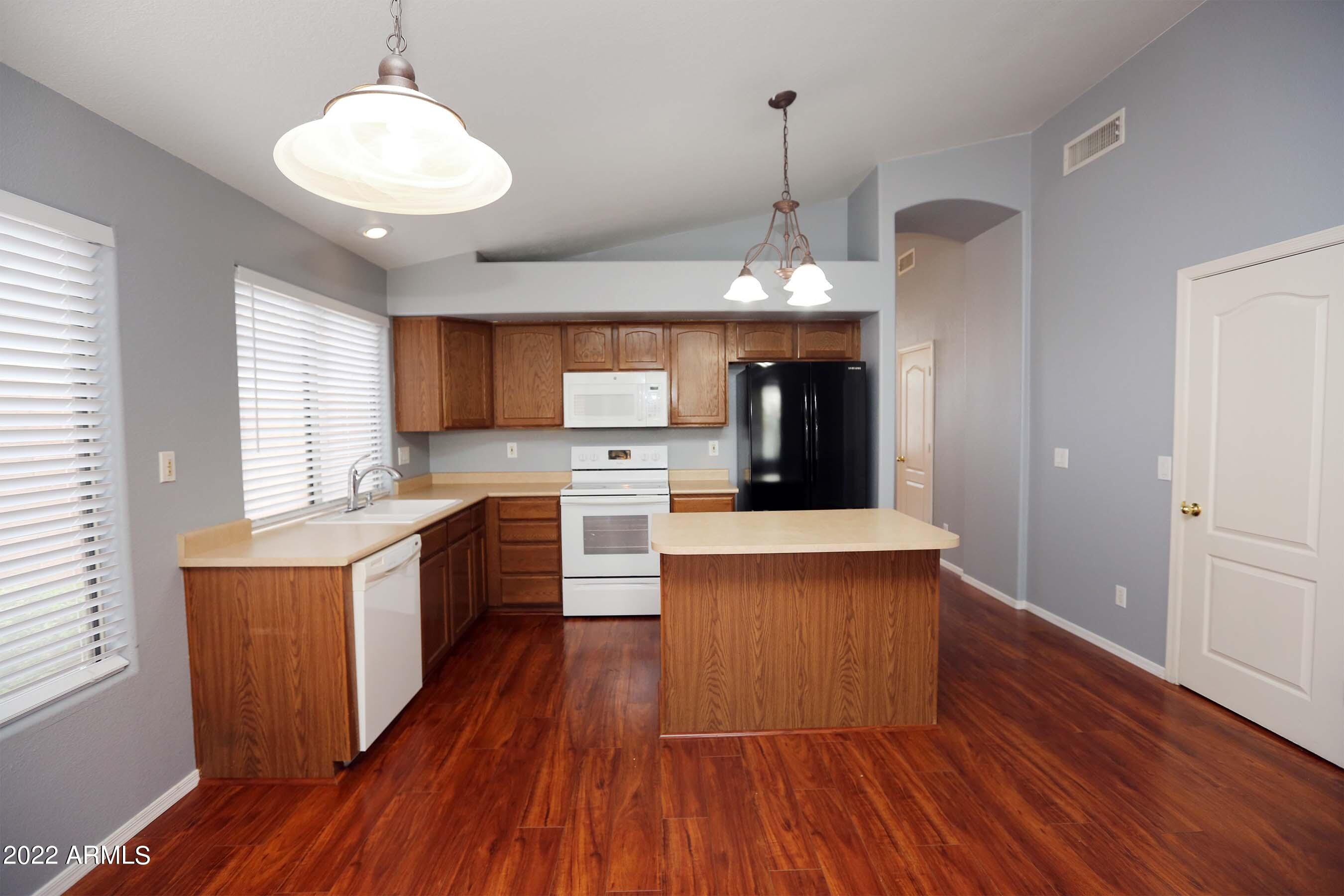 11217 West Edgemont Avenue Avondale, AZ 85392 - Photo 8 of 47 a large kitchen with stainless steel appliances granite countertop wooden floors a stove a sink and a refrigerator
