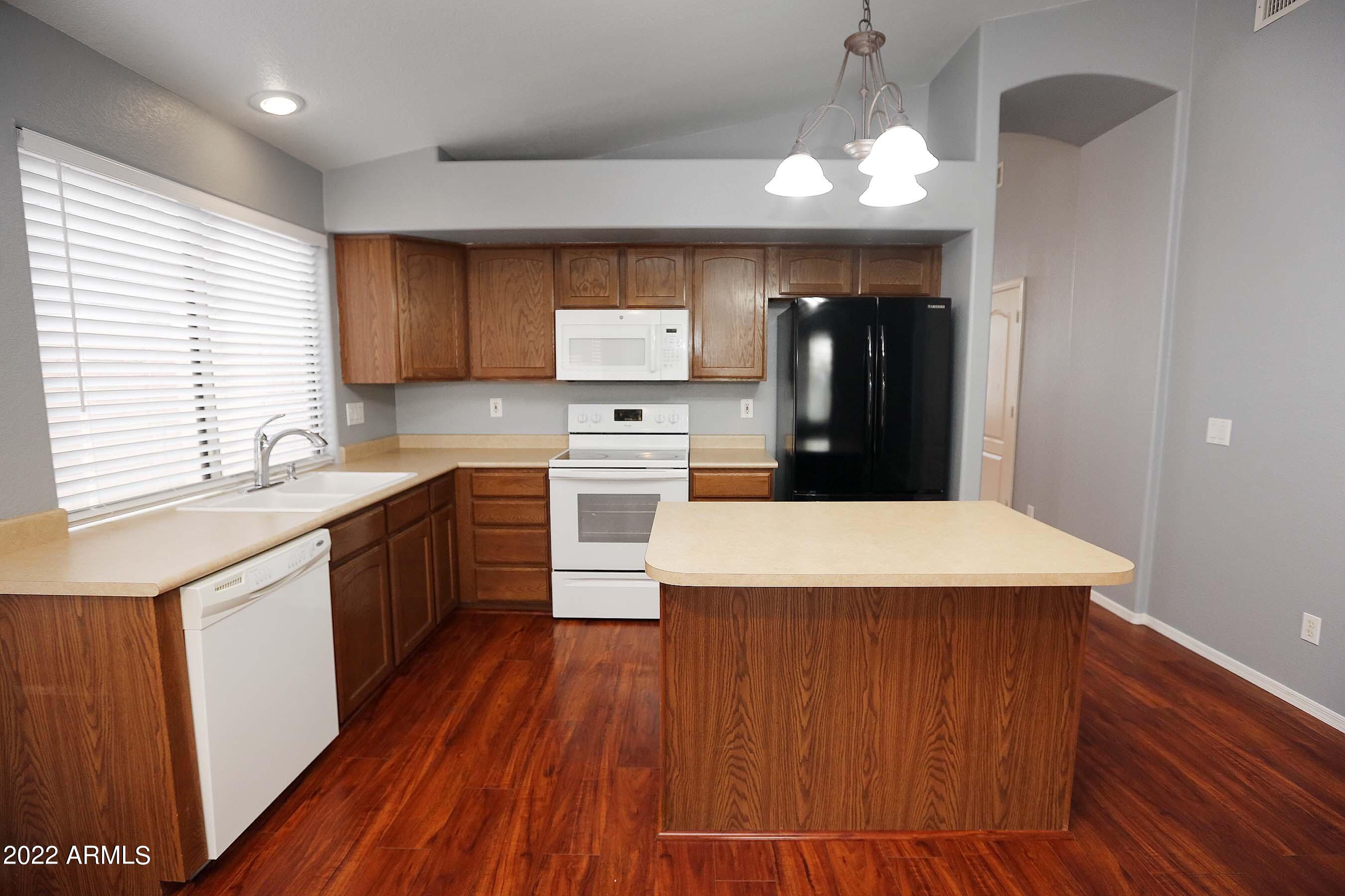 11217 West Edgemont Avenue Avondale, AZ 85392 - Photo 10 of 47 a large kitchen with stainless steel appliances a kitchen island hardwood floor sink stove dining table and chairs