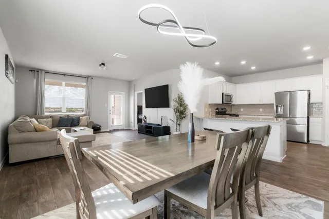 a living room with stainless steel appliances lots of furniture and kitchen view