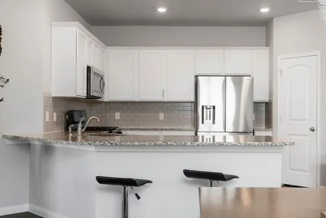 a kitchen with stainless steel appliances granite countertop a sink a stove and white cabinets