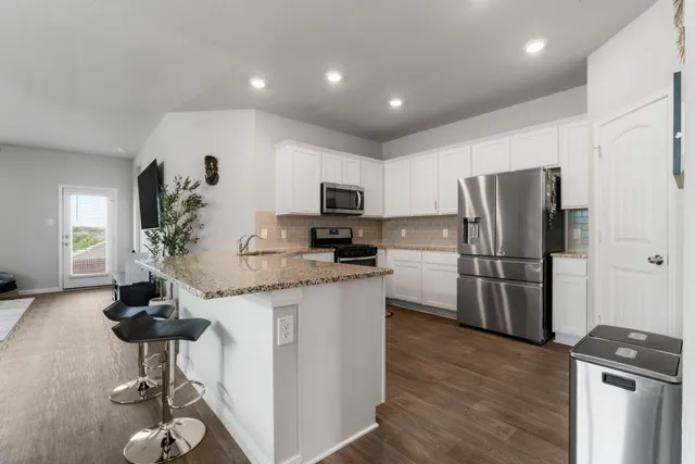 a kitchen with granite countertop a refrigerator stove and sink