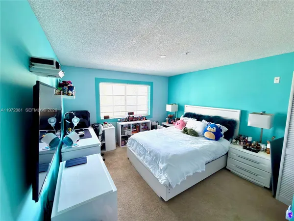 a bedroom with a bed a chandelier and a flat screen tv