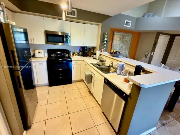 a kitchen with a sink a stove top oven a refrigerator and a window