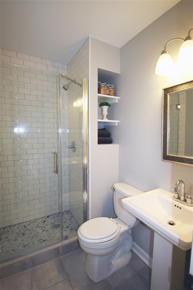 308 Lord Berkley Road Raleigh, NC 27610 - Photo 16 of 25 The master bathroom in this house may be small, but it is beautifully done! It has a shower with classic subway tile surround, river rock floor, and frameless glass shower door. There is built-in shelving and brand new pedestal sink and toilet. Master Bathroom