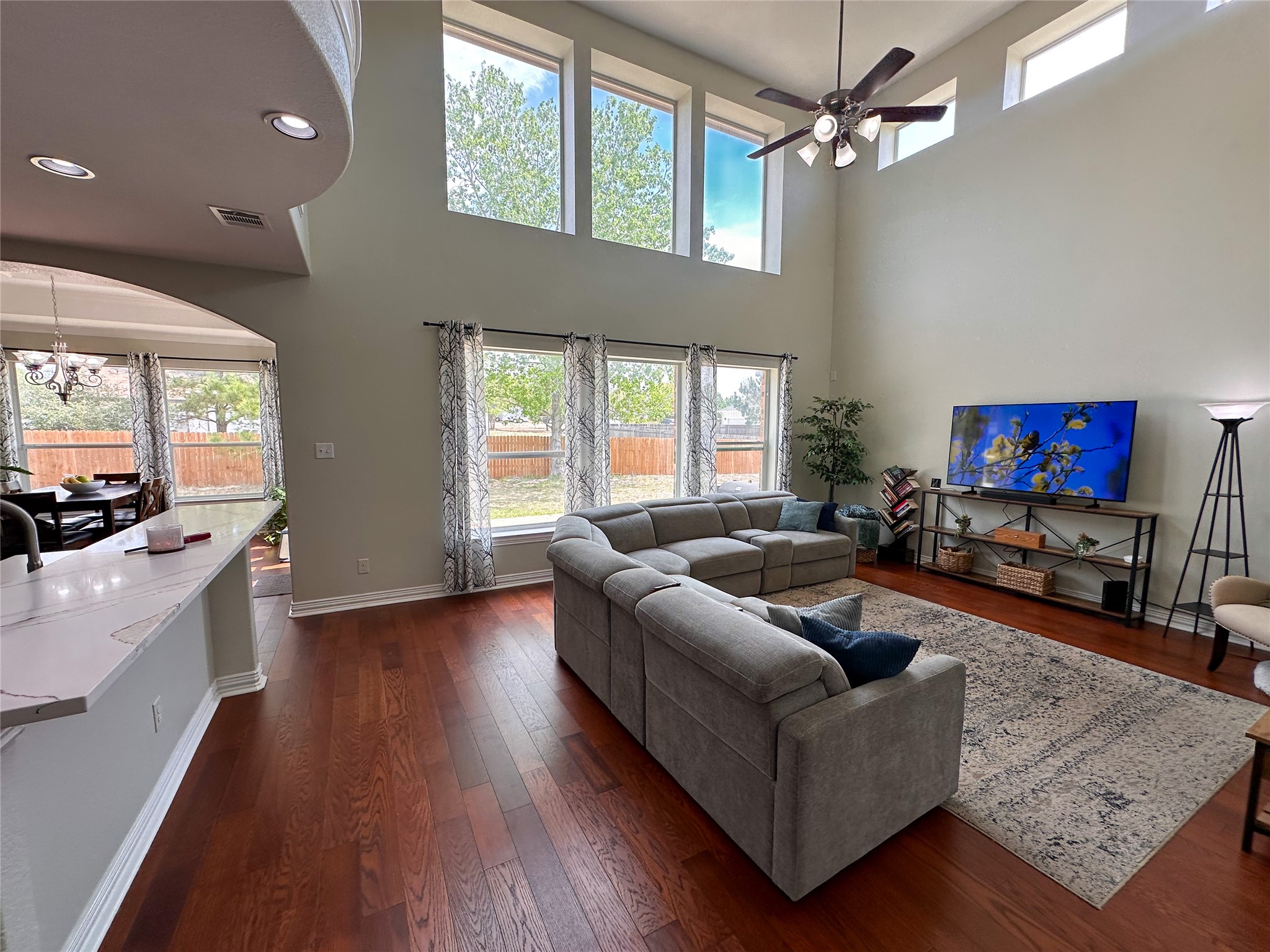 237 Cardinal Drive Paige, TX 78659 - Photo 5 of 37 Living room with dark wood-style floors, a high ceiling, arched walkways, suspended lighting, and a ceiling fan