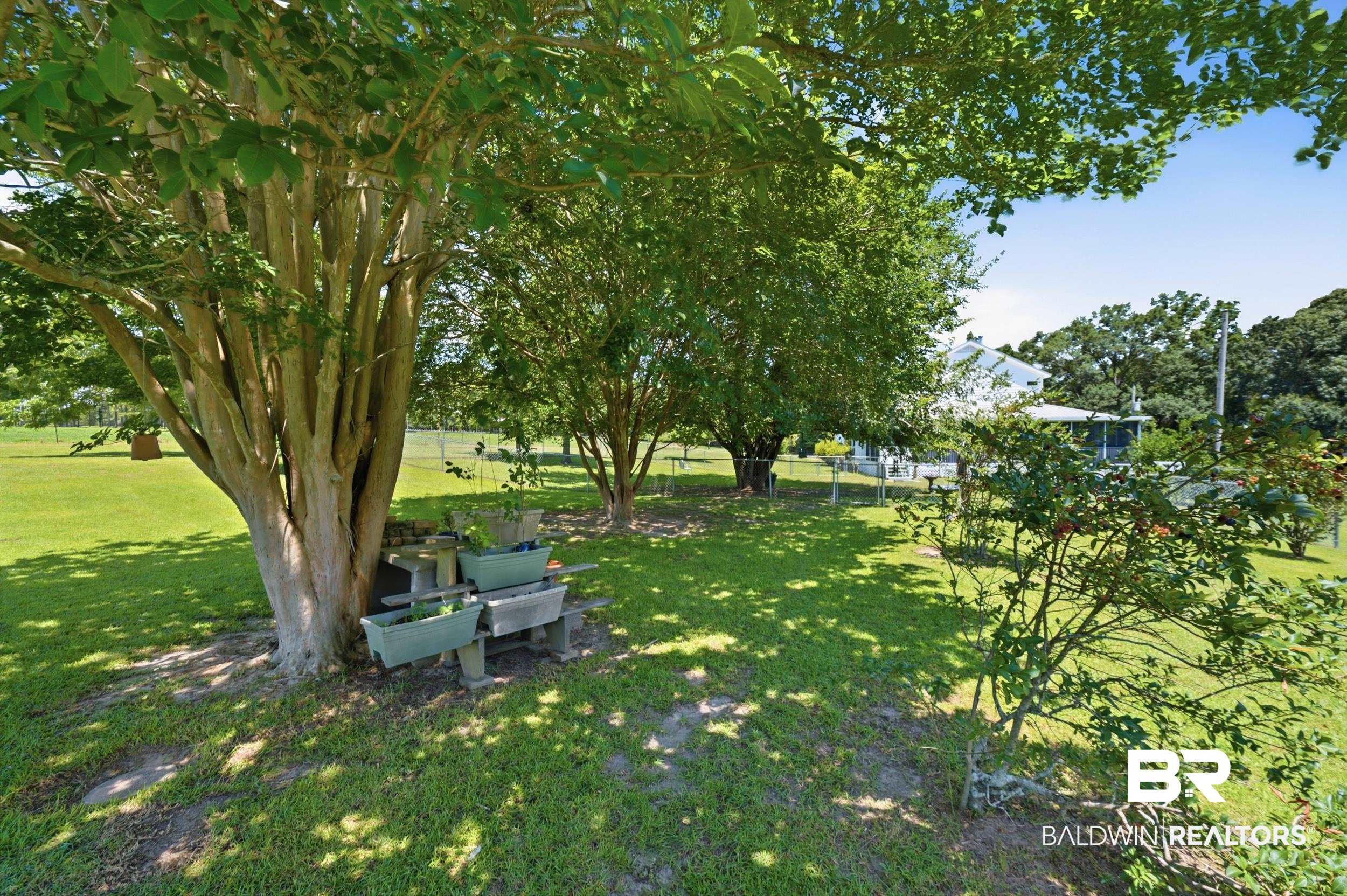 15855 Calvin Richerson Road Bay Minette, AL 36507 - Photo 68 of 83 Expansive grassy yard featuring mature trees, partial fencing, and a distant property structure