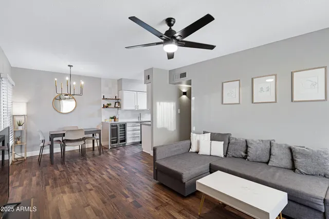 a living room with furniture kitchen view and a wooden floor
