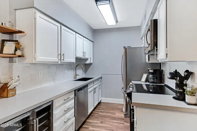 a kitchen with stainless steel appliances a sink dishwasher stove refrigerator and cabinets