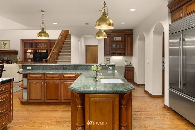 a kitchen with stainless steel appliances granite countertop a sink a stove and a wooden floors