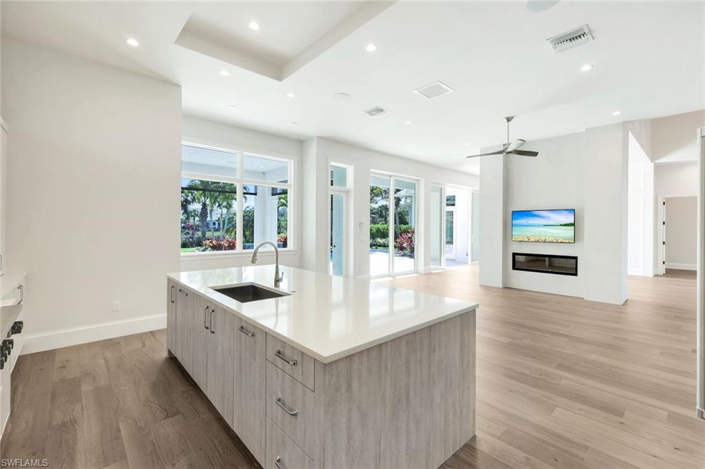 16716 Enclave Circle Naples, FL 34110 - Photo 11 of 50 Kitchen featuring modern cabinets, light wood-type flooring, light wood finish cabinets, an island with sink, and recessed lighting