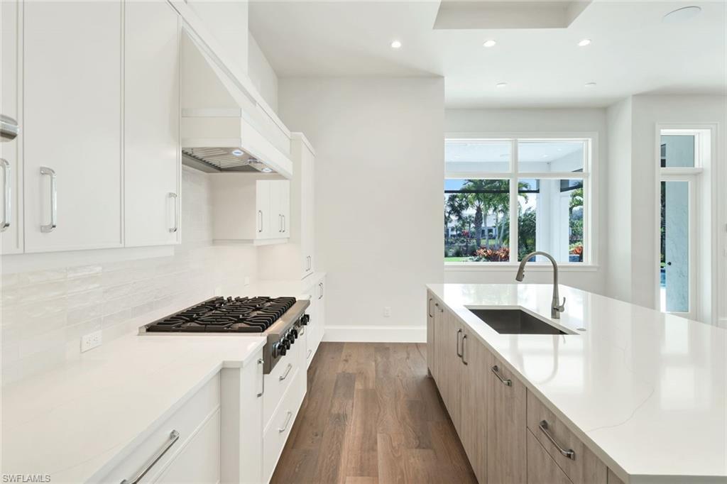 16716 Enclave Circle Naples, FL 34110 - Photo 12 of 50 Kitchen featuring dual tone cabinets, recessed lighting, dark wood finished floors, light stone countertops, and stainless steel gas cooktop