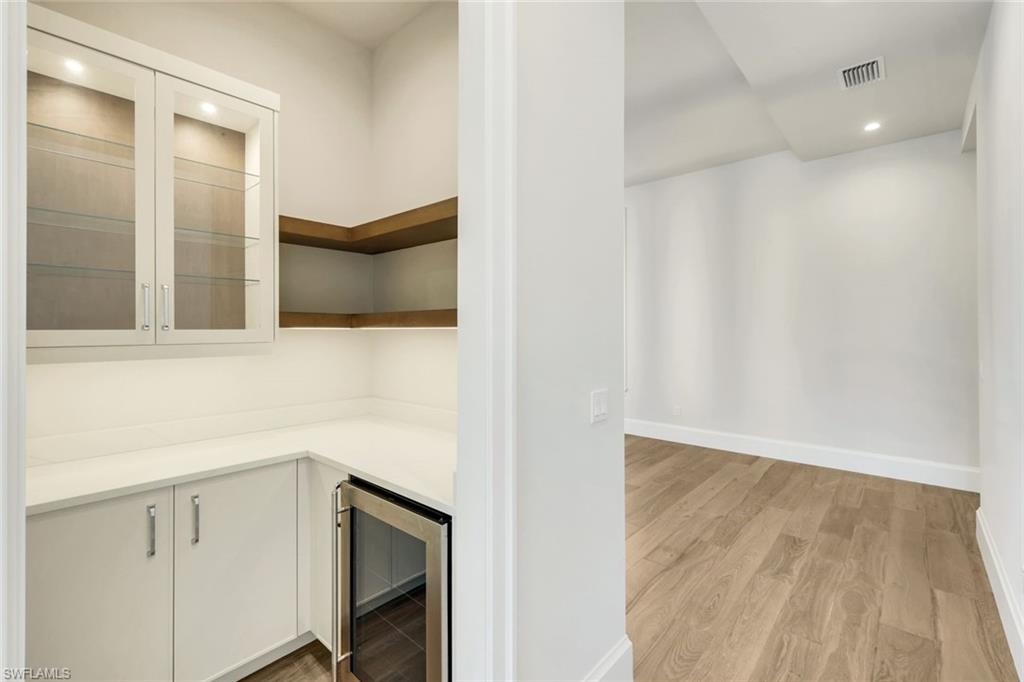 16716 Enclave Circle Naples, FL 34110 - Photo 15 of 50 Bar area featuring recessed lighting, beverage cooler, light wood-style flooring, light countertops, and white cabinetry