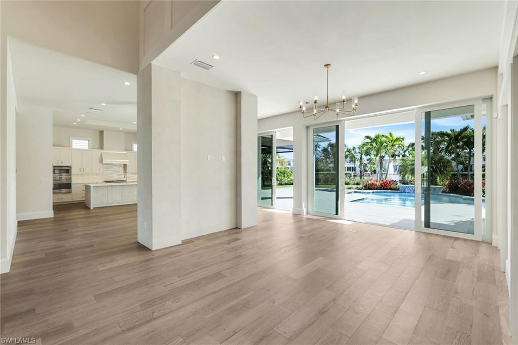 16716 Enclave Circle Naples, FL 34110 - Photo 17 of 50 Unfurnished living room with a chandelier and light wood-type flooring
